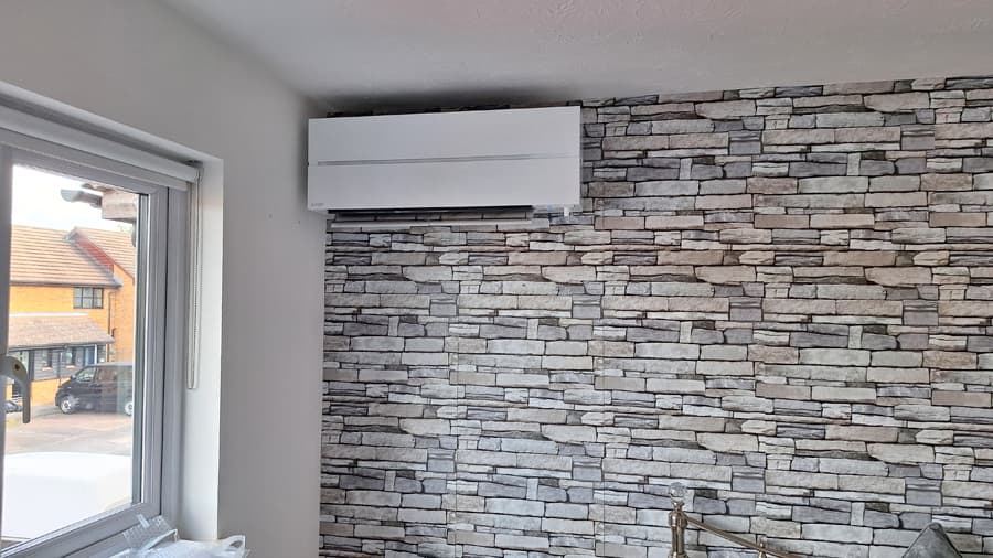 Air conditioning unit installed against stone feature wall in Kent home
