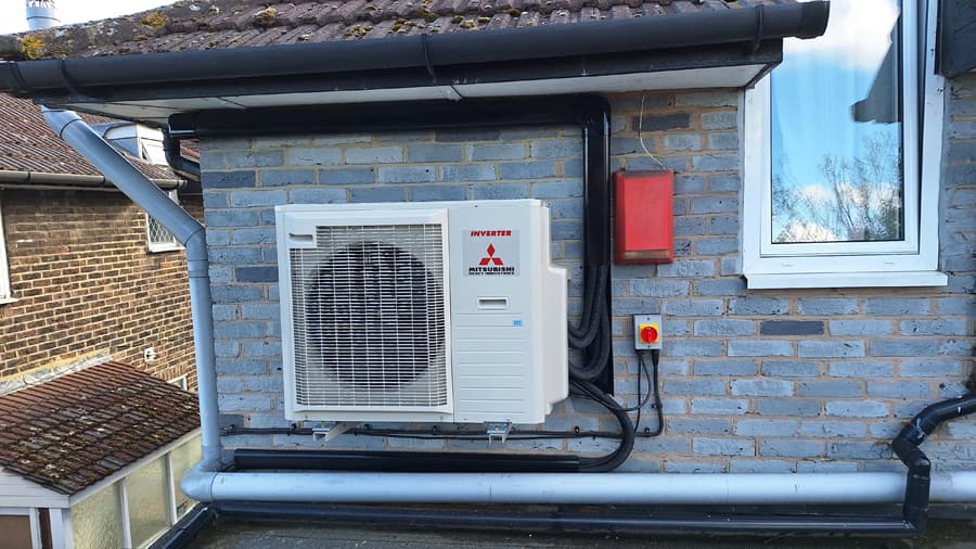 Mitsubishi air source heat pump outdoor unit on grey brick wall