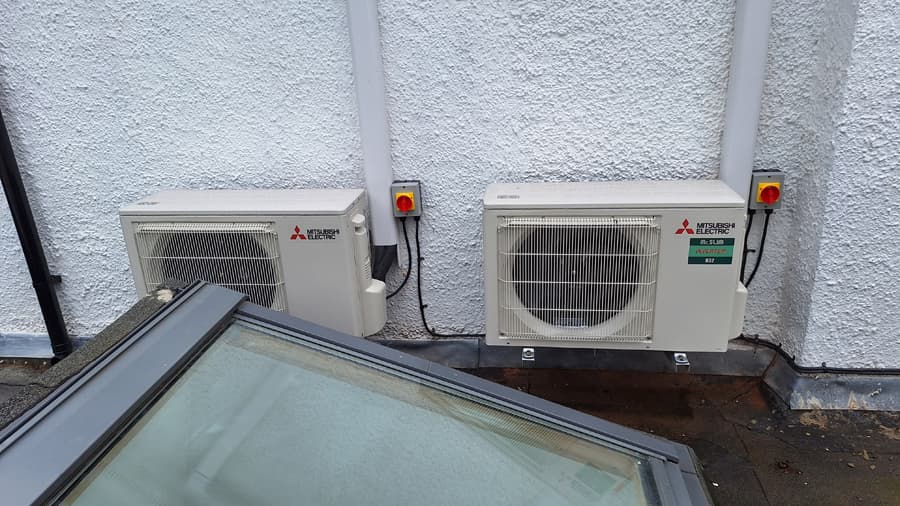 Twin Mitsubishi heat pump outdoor units mounted by skylight