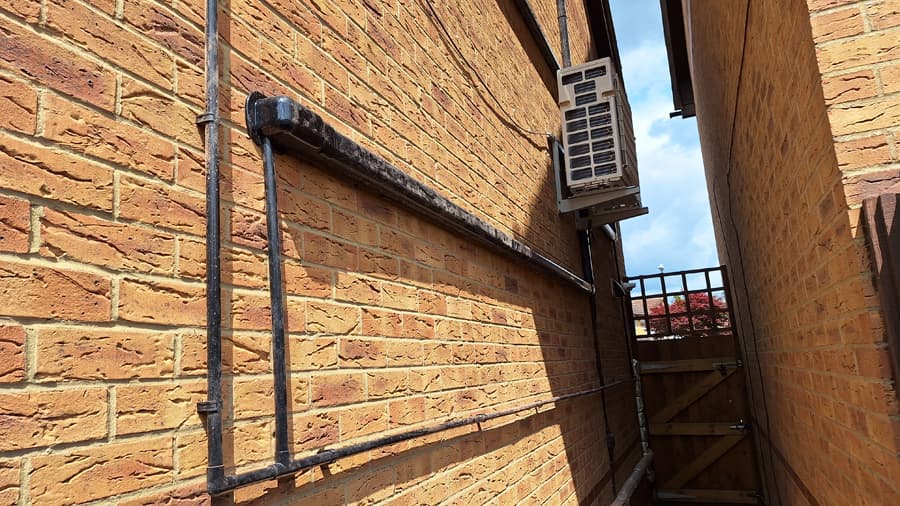 Heat pump outdoor unit installed in narrow yellow brick alley