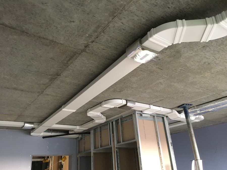 White MVHR plastic trunking with T-junction across ceiling