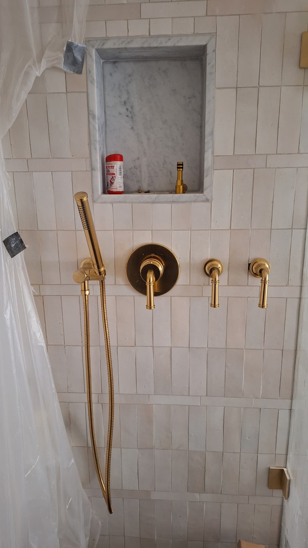 Brushed brass shower valve and handset on white tile