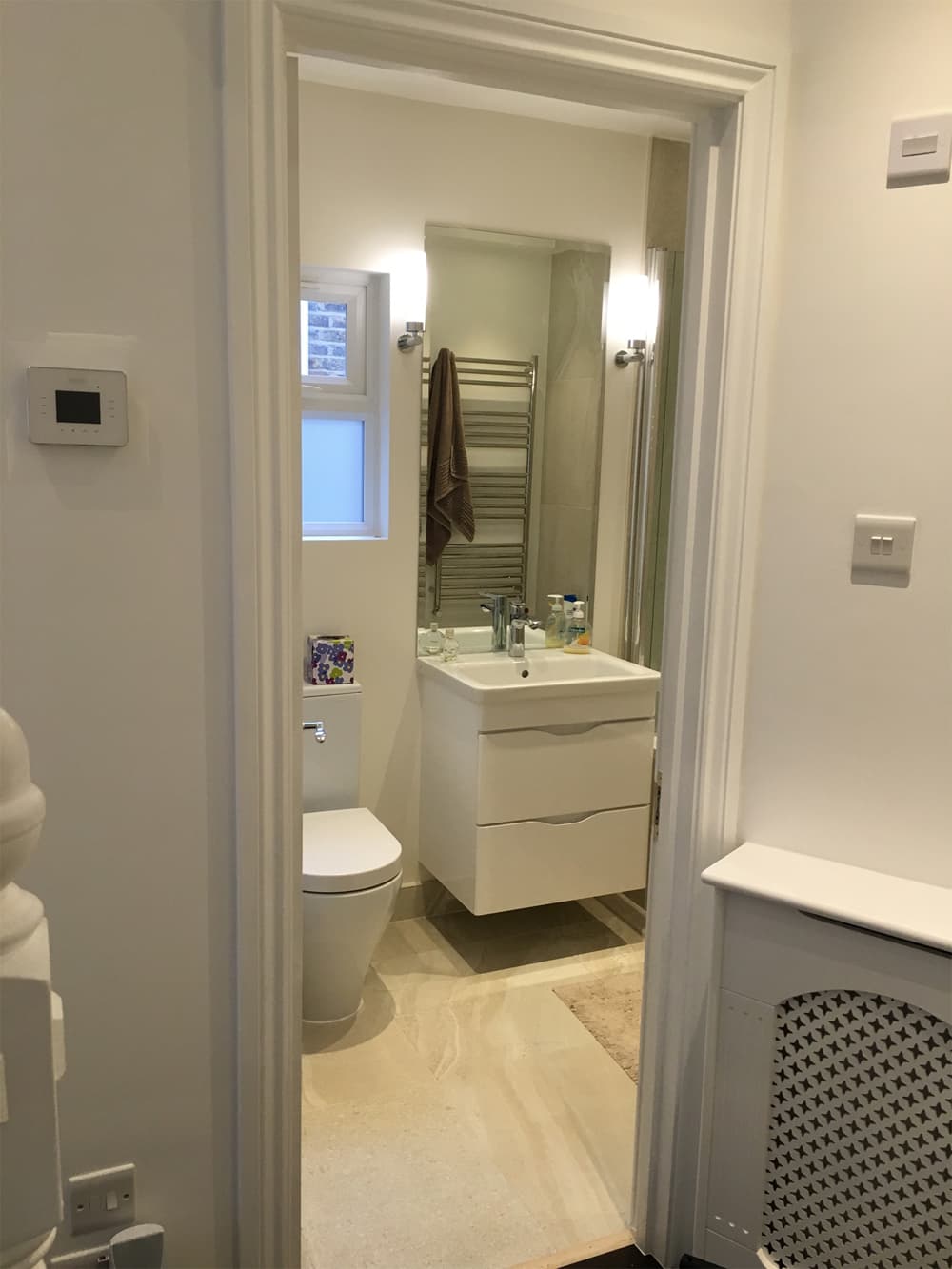 White en-suite bathroom with chrome heated towel rail and vanity unit