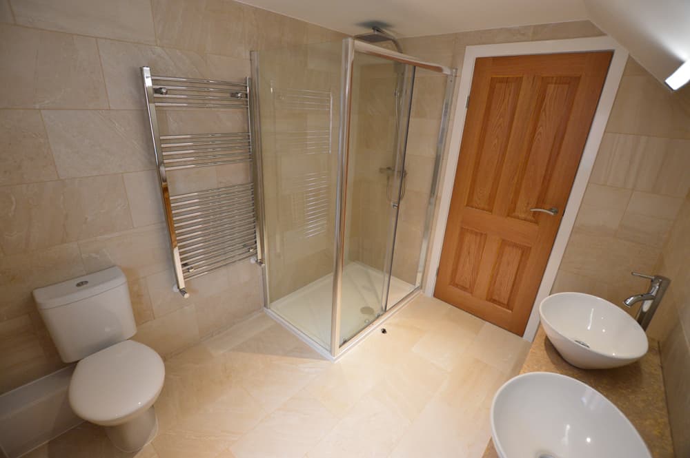 Beige tiled shower room with chrome heated towel rail
