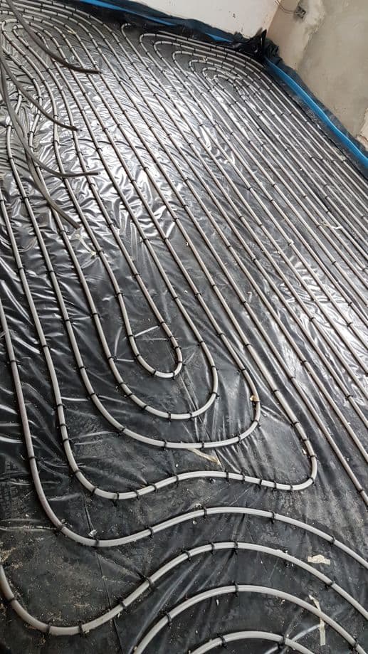 Close-up of underfloor heating pipe layout on insulation membrane