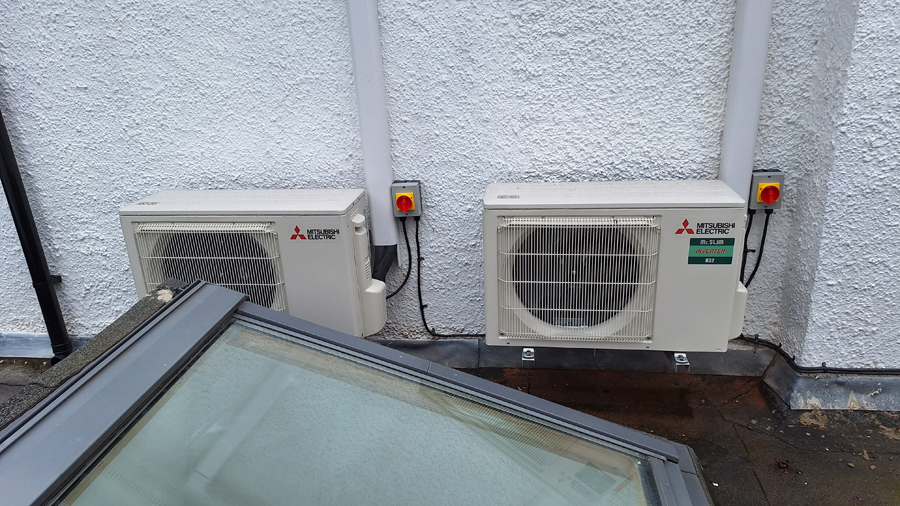 Twin Mitsubishi heat pump outdoor units mounted by skylight