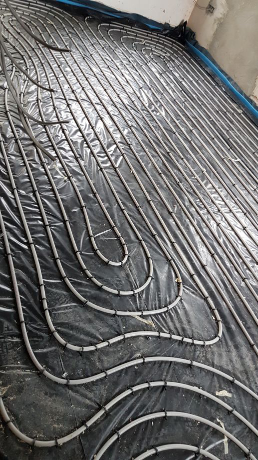 Close-up of underfloor heating pipe layout on insulation membrane